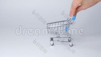 白色背景上的购物玩具手推车，有一些复制空间。 网上购物概念特写慢动作。