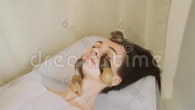 水疗程序大蜗牛在脸上。 在水疗中心的年轻女子接受了一个与蜗牛Achatina的面部按摩。 吃蜗牛