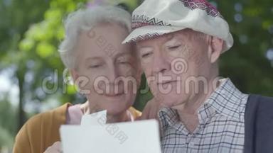 特写肖像，可爱的成人夫妇，看着<strong>老照片</strong>，回忆着坐在公园长凳上的快乐时刻