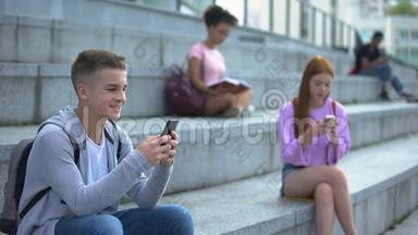 快乐男学生在户外玩智能手机游戏，玩小玩意成瘾，聊天