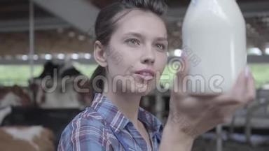 奶牛场年轻女<strong>职工</strong>画像，检查奶瓶特写中牛奶质量。 积极的农民