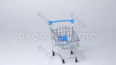 白色背景上的购物玩具手推车，有一些复制空间。 网上购物概念特写慢动作。