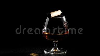 豪华白兰地。 玻璃上的雪茄与金色干邑旋转在黑色桌子上的黑色背景。 白兰地，白兰地，嗅探器。