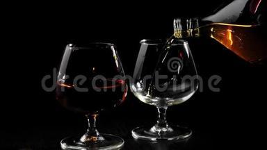 豪华白兰地。 手把金白兰地从一个圆形的瓶子里倒入一个玻璃杯里，放在旋转的黑色桌子上，靠近玻璃杯和白兰地。