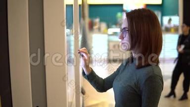 一位年轻女子在购物中心的触摸<strong>终端</strong>点菜。 现代技术。 在食品法庭上