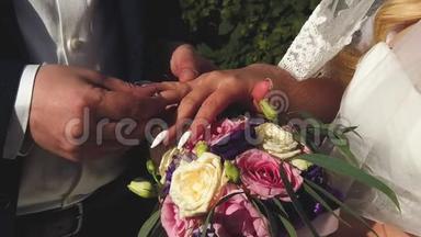 结婚典礼。 新郎和新娘在夏日公园的背景上互相戴上结婚戒指