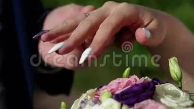 结婚典礼。 新郎和新娘在夏日公园的背景上互相戴上结婚戒指