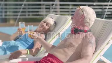 成熟的夫妇躺在游泳池附近的日光浴床上喝着果汁，交谈着，微笑着。 充满爱意的家庭。 康乐及文化事务署