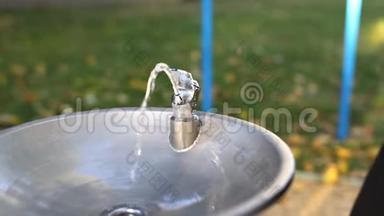 秋季户外<strong>儿童游乐场</strong>附近的城市公园，带有饮用水喷泉的金属水龙头。 饮用水