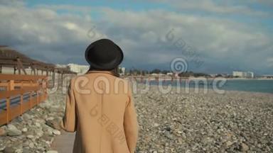 浪漫的女人在阳光明媚的秋日漫步在鹅卵石岸上