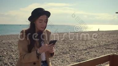 独自一个漂亮的女士在海边的智能手机上用<strong>无线上网</strong>聊天