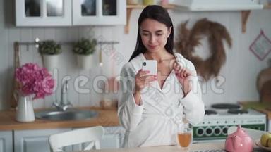 穿着<strong>白色浴袍</strong>的女人在手机上发信息，用手机在家工作