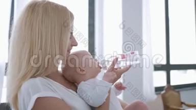 <strong>婴儿</strong>护理，年轻快乐的母亲<strong>抱着婴儿</strong>，从瓶子里喝水