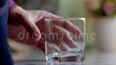一个人从一个透明的水壶里倒水到水玻璃里