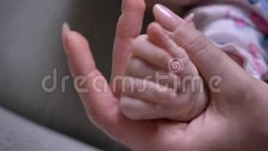 特写镜头的妈妈和可爱的新生宝宝双手紧紧相握..