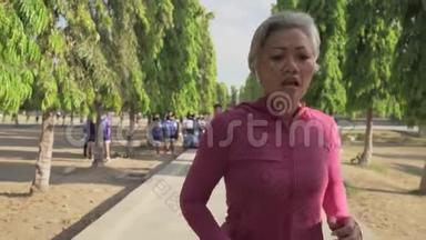 索洛莫万向节跟踪迷人的中年女士在城市公园跑步快乐。 40多岁的美女正在慢跑