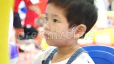 一个亚洲小女孩在购物中心玩街机汽车驾驶游戏