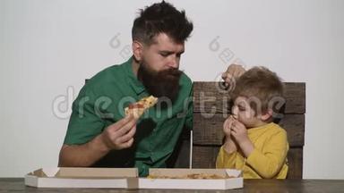 父子共进午餐.. 给孩子吃披萨。 人`午餐.. 留胡子的人是在餐桌上吃饭的小男孩。 意大利