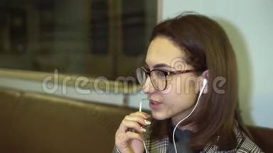 一位年轻女子正在地铁列车上通过耳机打电话。 旧地铁车