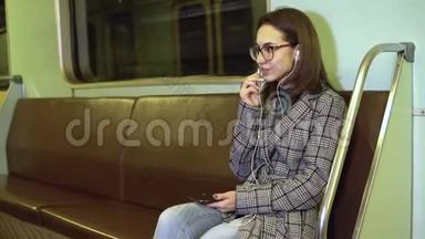 一位年轻女子正在<strong>地铁</strong>列车上通过耳机打<strong>电话</strong>。 旧<strong>地铁</strong>车