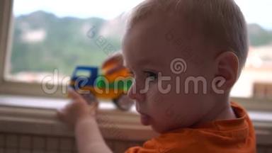 一个可爱的小男孩望着窗外，慢悠悠地在卡车旁玩耍