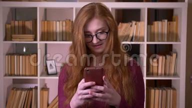 在大学里，戴<strong>着眼</strong>镜的年轻红发美女戴<strong>着眼</strong>镜在手机上浏览的特写肖像