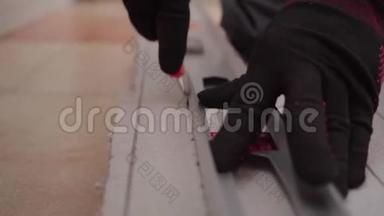 关闭手工人在黑色和红色手套使用金属标尺切割片的隔热灰色。