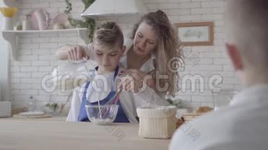 漂亮的女人和她十几岁的儿子在厨房做饭，那个男孩帮妈妈做食物。 妈妈在碗里<strong>倒牛奶</strong>