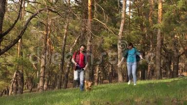 幸福的一对夫妇和奥巴克一起穿过树林。 一家人和狗在树林里旅行。 旅行者爸爸，女儿，宠物