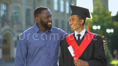 父亲抱着毕业的儿子，带着文凭，<strong>学历</strong>，成功，感到自豪
