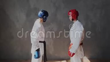 两个年轻强壮的青少年戴着防护头盔和拳击手套，热身肌肉，采取战斗姿势，看着