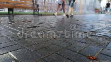 夏天下雨后，人们在潮湿的沥青上行走。 太阳照耀着，行走的人的轮廓模糊了，有了它