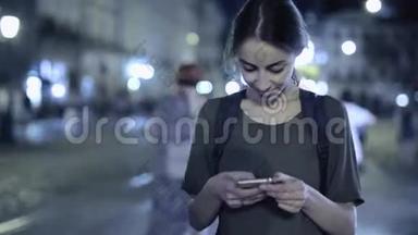 年轻漂亮的女人手拿着电话站在利沃夫市中心<strong>拥挤</strong>的<strong>街道</strong>上，时间流逝的视频