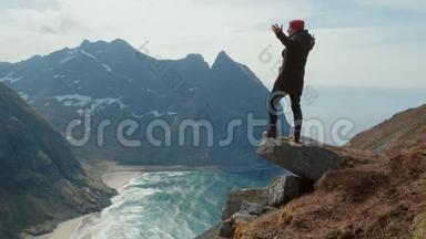 挪威的一个徒步旅行者站在山的边缘，风很大