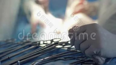 外科治疗，护士双手戴着血手套，靠近手术工具，接近医生的模糊背景