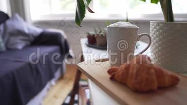 软<strong>沙发背景</strong>上的热咖啡和自制牛角面包-湿