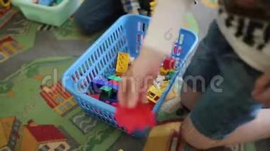 幼儿玩彩色塑料玩具.. 汽车的游戏。 两个男孩收集彩色塑料制品