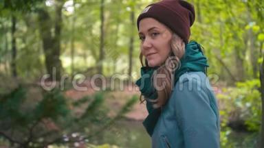 一个年轻的女人，一个戴着红色帽子和蓝色夹克的女孩，在公园里邀请她一起去。 微笑着走进