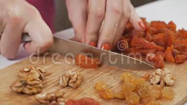 一位年轻的家庭主妇用一把刀在砧板上切果干杏子. 健康的饮食观念。 慢动作