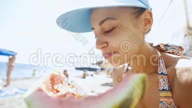 在海滩上吃一大块西瓜的滑稽少女的广角镜头