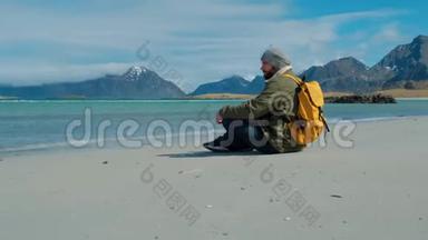 留胡子的人坐在沙滩上，背着黄色的背包，时髦的人欣赏着<strong>蓝色</strong>的<strong>大海</strong>，看着<strong>大海</strong>