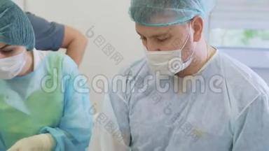 两名医生和护士在手术室手术期间戴无菌口罩和衣服的画像