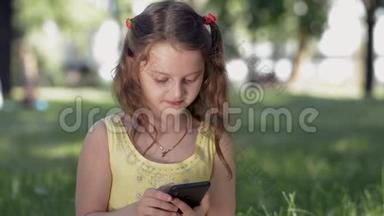 在阳光明媚的夏日，一个<strong>女孩</strong>坐在公园的草地上，用智能手机与<strong>社交网络</strong>中的朋友交流。 微笑