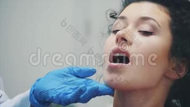 牙医和病人。 年轻漂亮的牙医在牙医`办公室修理一位漂亮年轻女子的牙齿。 牙医