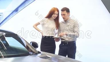 年轻夫妇在汽车经销商中选择豪华车，看内饰和汽车特点