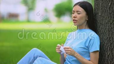 年轻女子打喷嚏，坐在树上，患有春季过敏症，药物