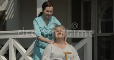 理疗师在医院康复中心户外用红相机拍摄的阳光日镜头按摩老年妇女