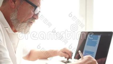 在家<strong>用笔</strong>记本电脑工作的老人。 年迈的祖父戴着眼镜，在客厅里<strong>用笔</strong>记本电脑工作