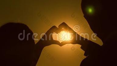 一对相爱的夫妇的剪影在明亮的阳光下显示了一种心灵的象征。 太阳在手里。 恋人的共同工作