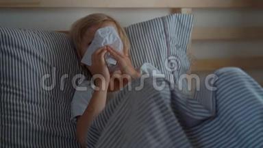 一个男孩用餐巾纸擦鼻涕时的超慢镜头。 在床上生病的小男孩。 婴儿流感概念
